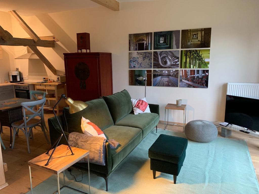 een woonkamer met een groene bank en een tafel bij Kranichhof - Studio, Loft & Atelier in Zossen