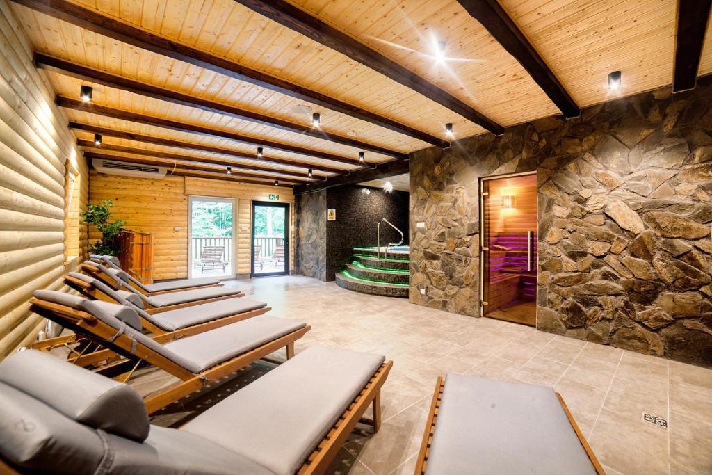 Strefa relaksu SPA z leżankami, drewnianym sufitem, kamienną ścianą i podświetlaną wanną