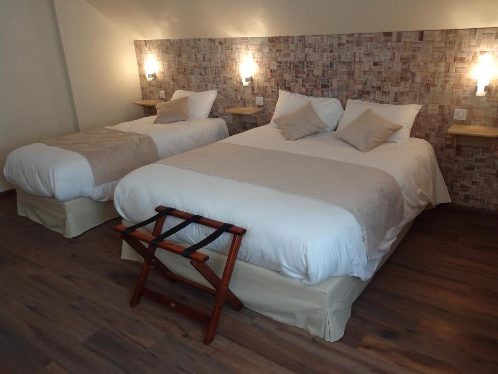 two beds in a hotel room with two tables at LE Relais des Anges in Rupt-sur-Moselle