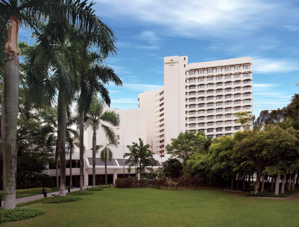 a large white building with palm trees and a park at Dorsett Grand Subang Hotel in Subang Jaya
