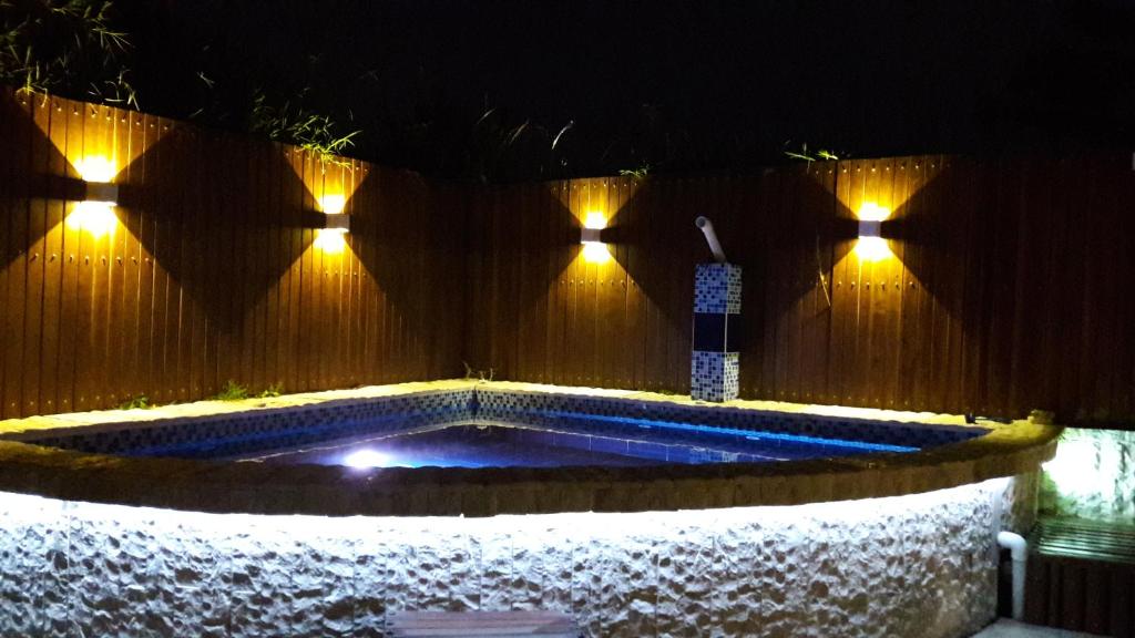 - une piscine avec des lumières sur une clôture en bois dans l'établissement El Portal de Mariana, à Pereira