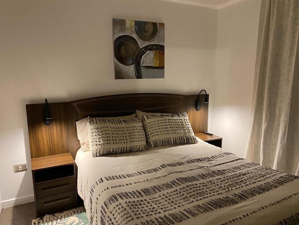 1 dormitorio con 1 cama con cabecero de madera en Departamento entero Reñaca - Jardín del mar, en Viña del Mar