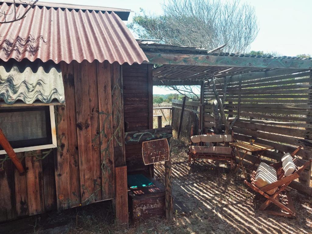Cabaña de madera con techo oxidado y silla en El Cusifai, en Barra de Valizas