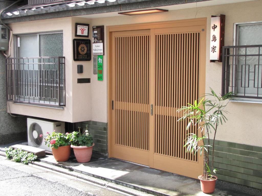 una puerta delantera de un edificio con macetas en Ryokan Nakajimaya, en Kioto