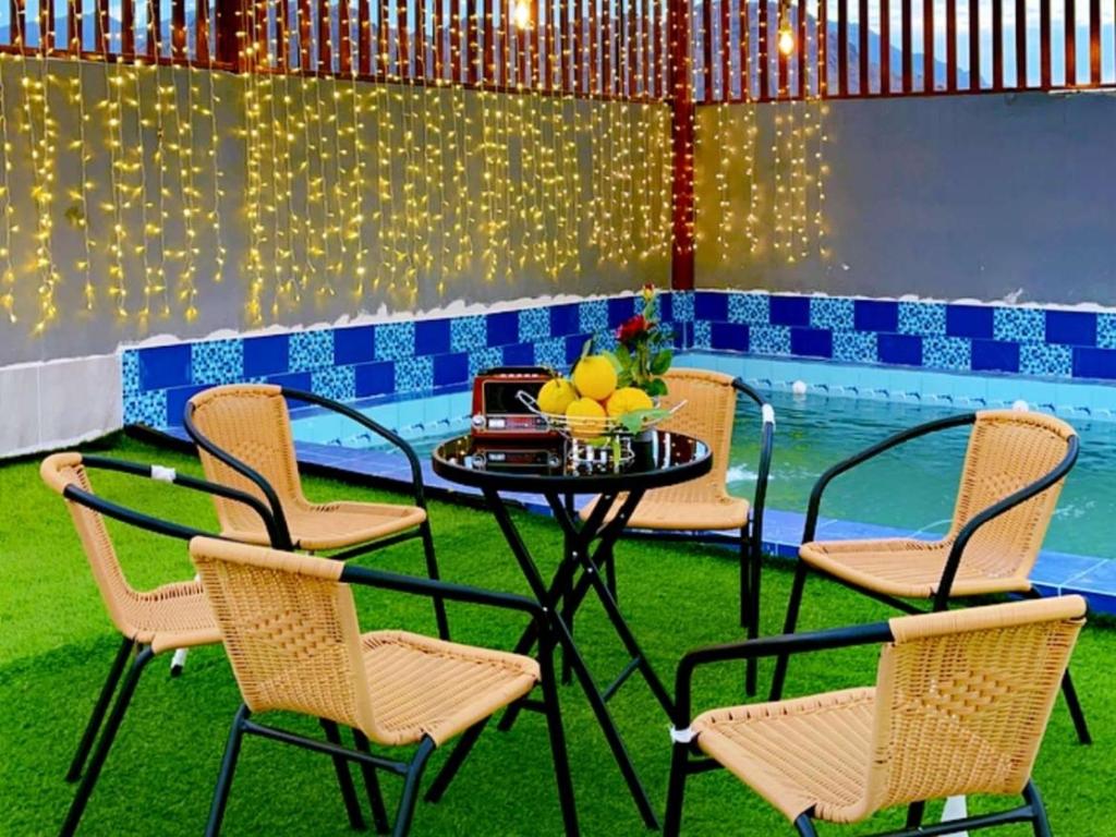 - une table et des chaises dans une chambre avec piscine dans l'établissement أستراحة مون لايت الريفي, à Al-Ula