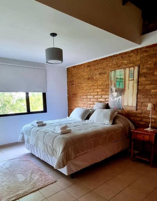 een slaapkamer met een groot bed en een bakstenen muur bij Duplex Boulevard A in Viedma