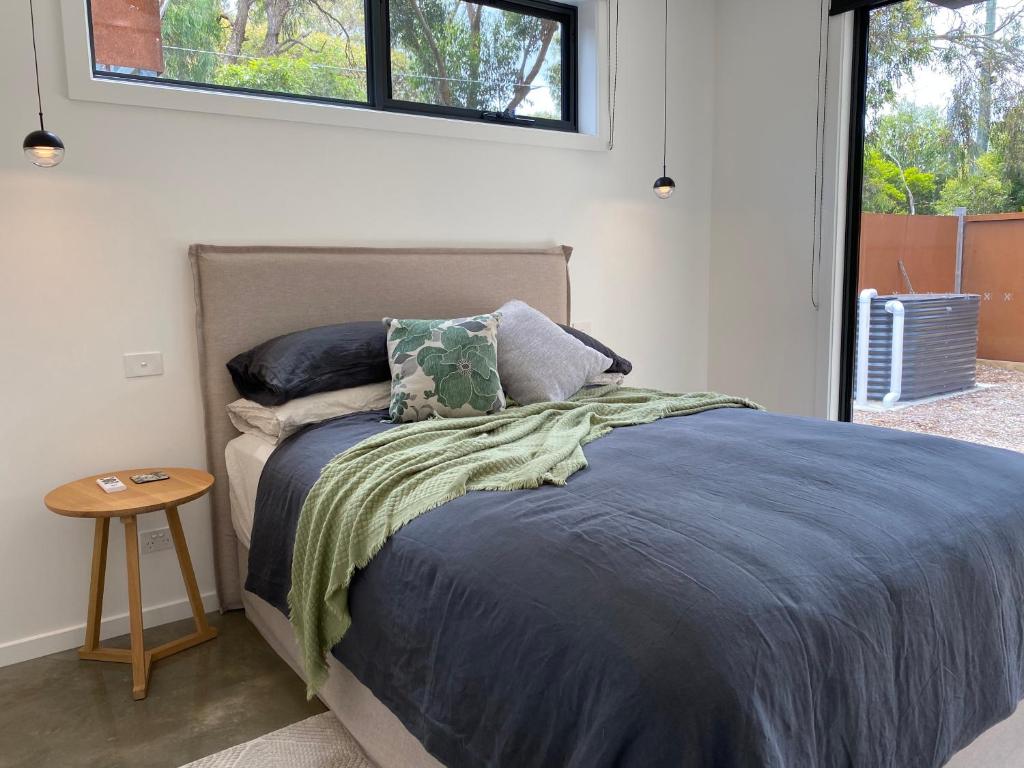 a bedroom with a bed and a table and a window at The Little House in Inverloch