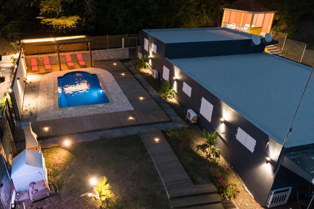 - une vue de tête sur une maison avec une piscine la nuit dans l'établissement La villa IXORAS, à Le Robert
