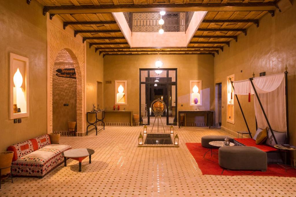 uma grande sala com sofás e mesas num edifício em Riad Azawad em Merzouga