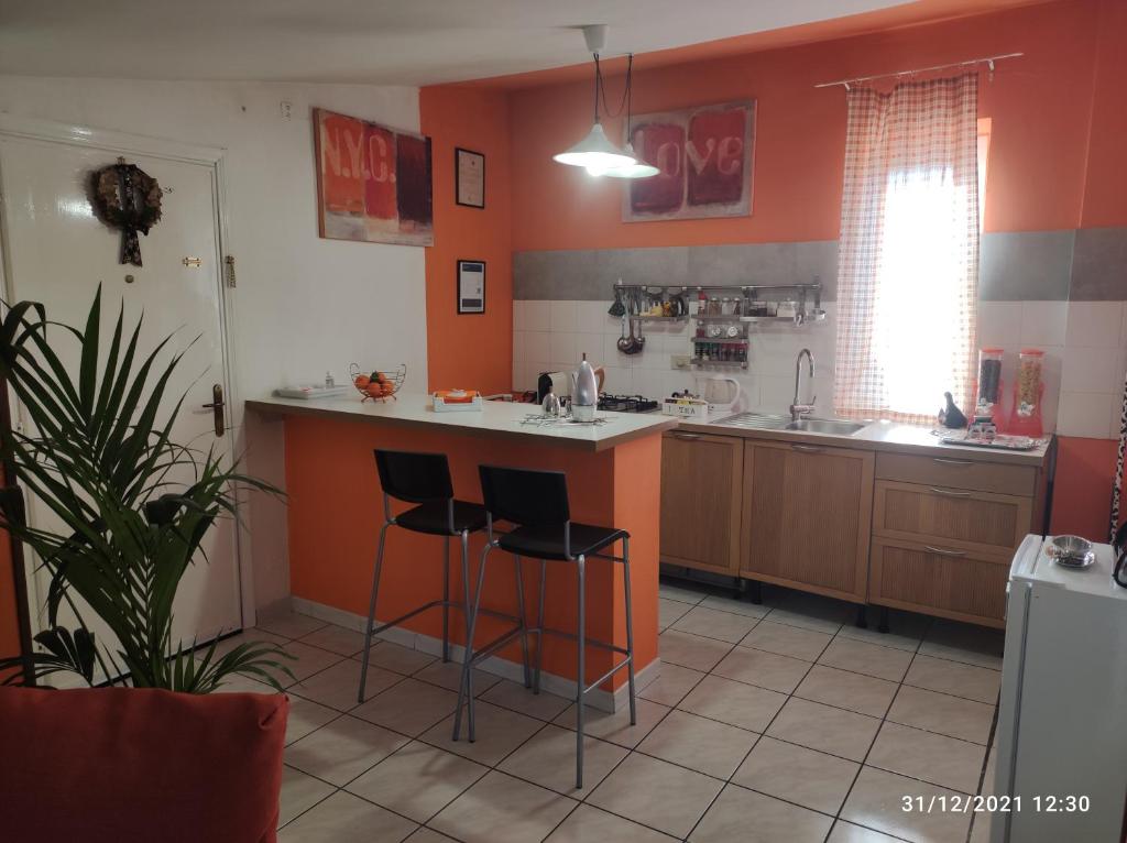 een keuken met oranje muren en 2 barkrukken bij La casa di Rick in Ronciglione