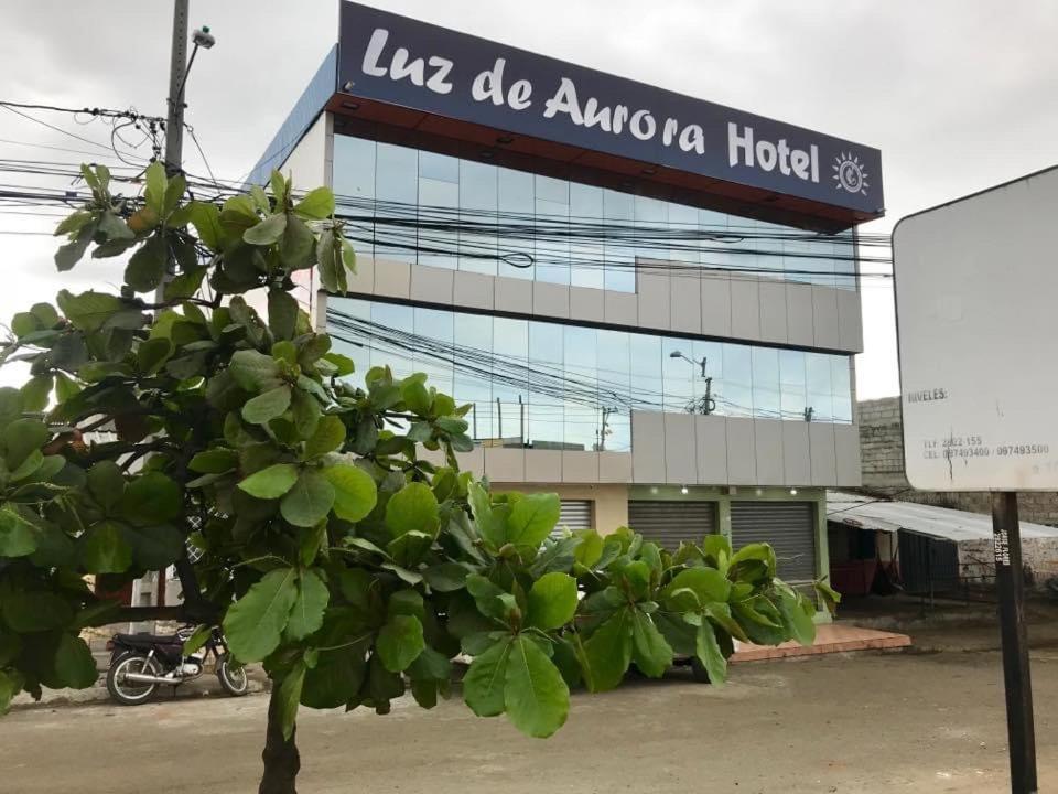 uma árvore em frente a um edifício com uma placa em Luz de Aurora HOTEL em Manta