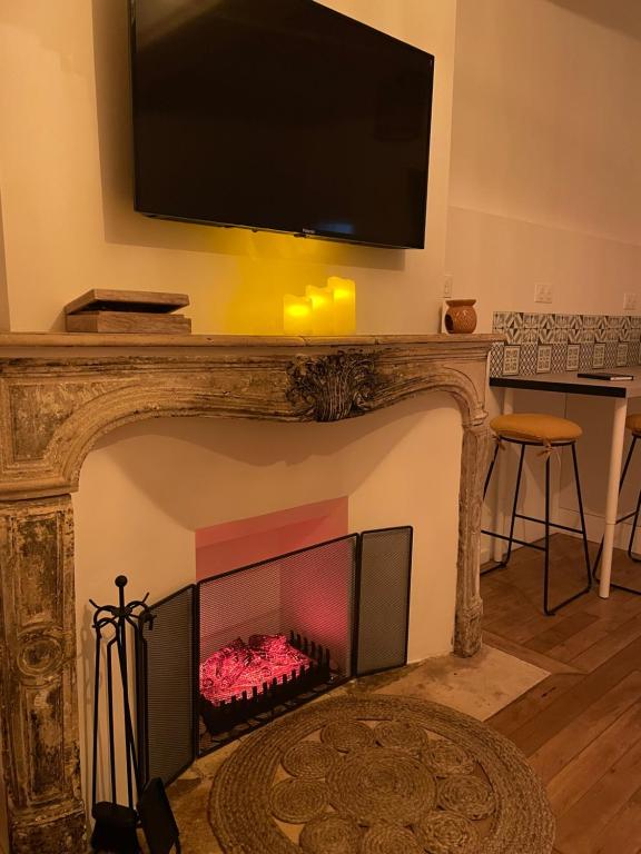 sala de estar con chimenea y TV encima. en Bohème Spa Appartement privatif avec jacuzzi, en Orléans