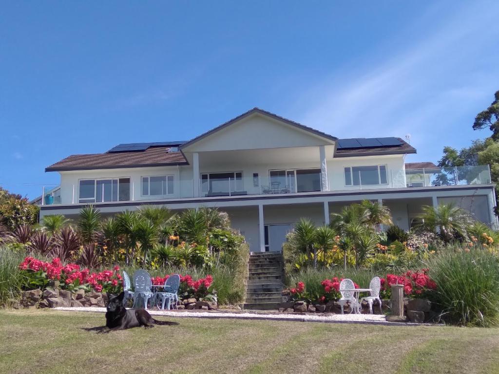 a house with chairs and flowers in front of it at Taipa Coastal Retreat in Taipa