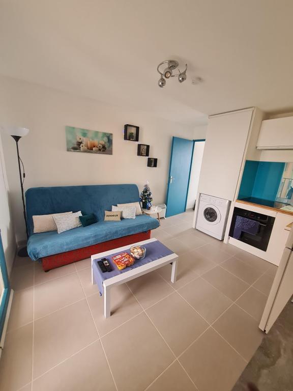 uma sala de estar com um sofá azul e uma mesa em appartement vue mer pour 4 personnes accès direct plage wifi haut débit gratuit em Le Barcarès