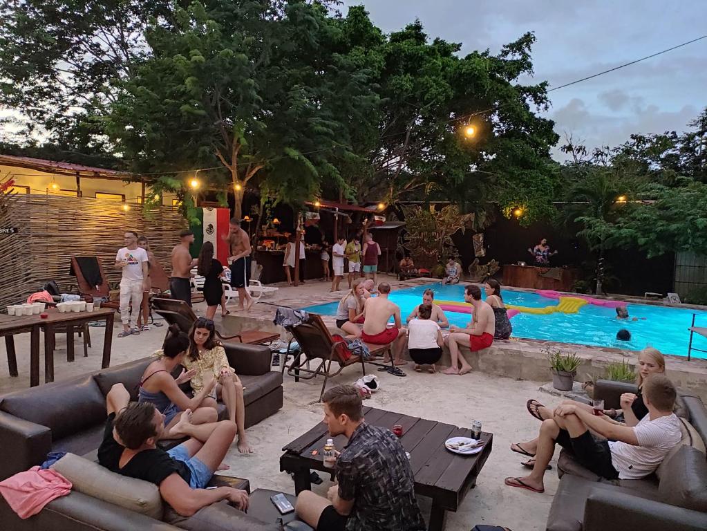 a group of people sitting around a pool at night at The FREE Hostel - Leisure Travel Only in Tulum