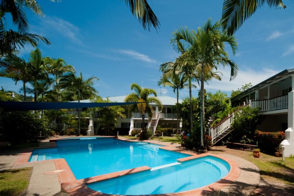 een zwembad in een tuin met palmbomen bij Mango House Resort in Airlie Beach