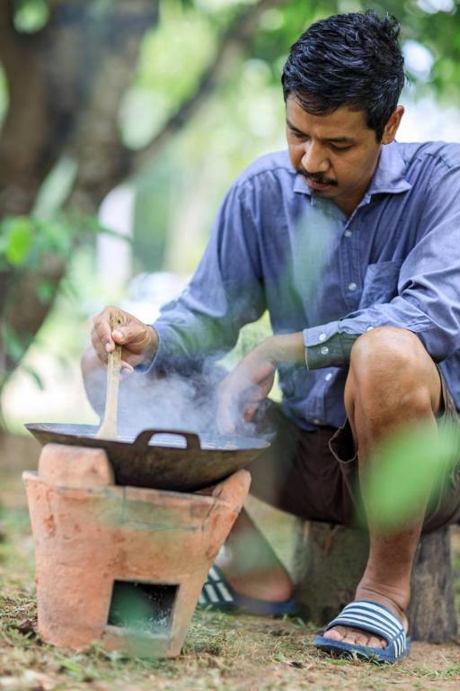 a man cooking food in a pan on a grill at Bang Po Hut in Ban Bang Po