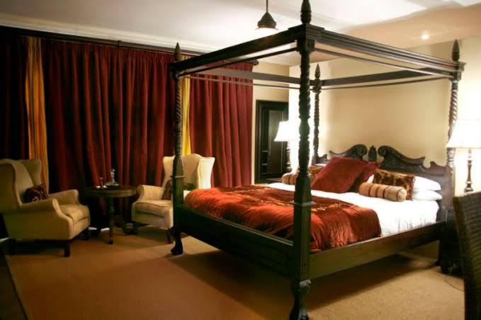 a bedroom with a canopy bed and a chair at Umdlalo Lodge in Port Shepstone