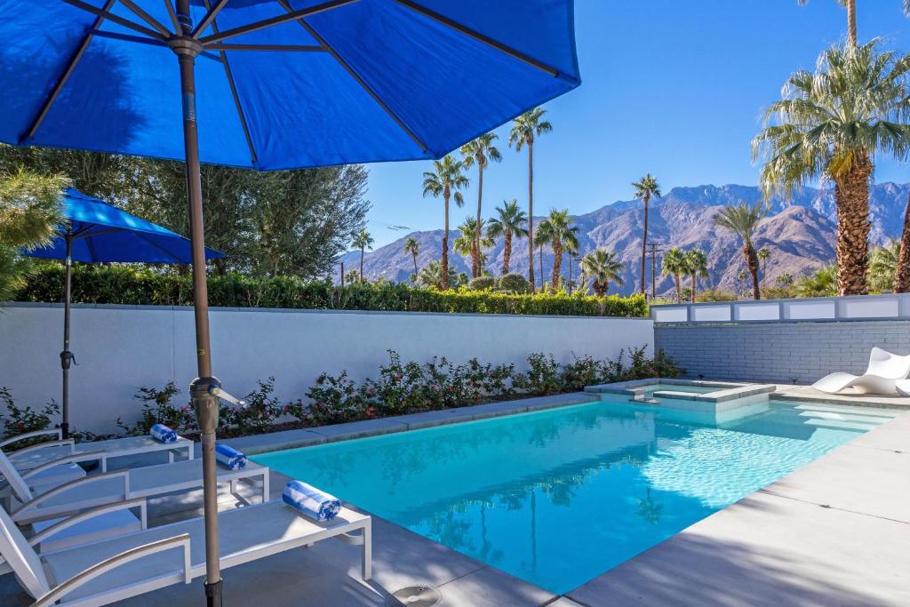 einen Pool mit Stühlen und einem Sonnenschirm in der Unterkunft Happy Hour in Palm Springs