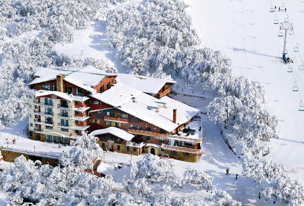 a ski lodge in the snow with snow covered trees at Hotel Pension Grimus in Mount Buller