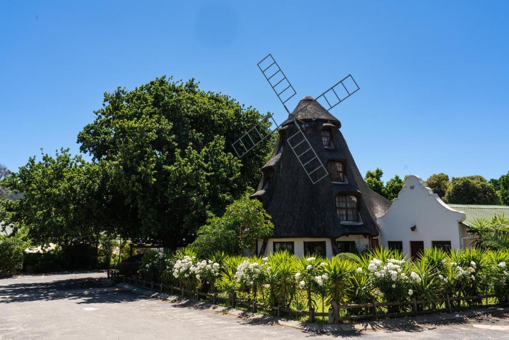 une maison avec un moulin à vent en haut dans l'établissement De Hollandsche Molen, à Hou Moed