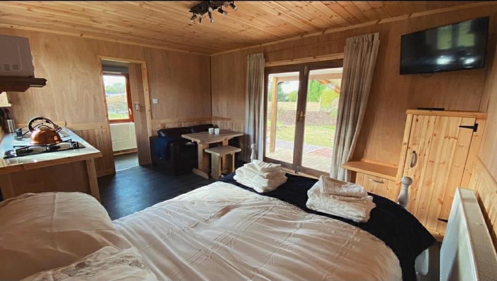 a bedroom with a bed in a room with a window at Beautiful Wooden tiny house, Glamping cabin with hot tub 3 in Tuxford