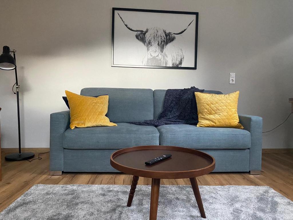 ein Wohnzimmer mit einem blauen Sofa und einem Tisch in der Unterkunft Am Taubenhaus FEWO Spatzennest NEU in Traben-Trarbach