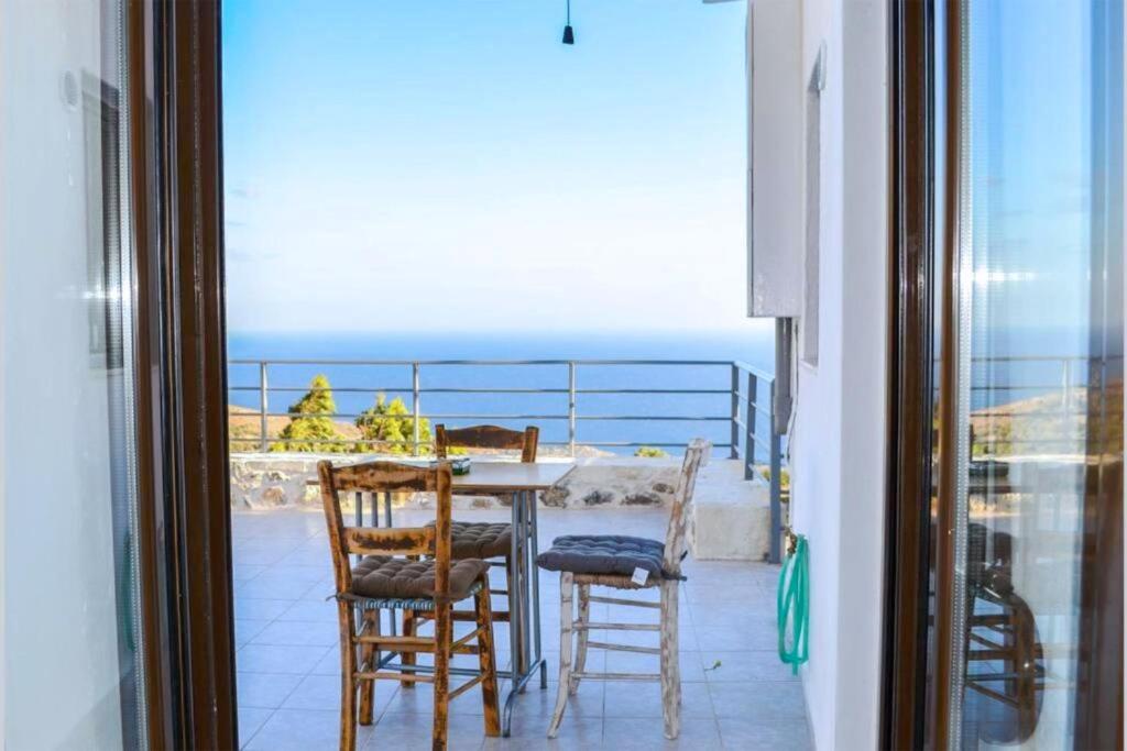 a table and chairs on a balcony with a view of the ocean at Villa Irena panoramic sea view in Agalianós