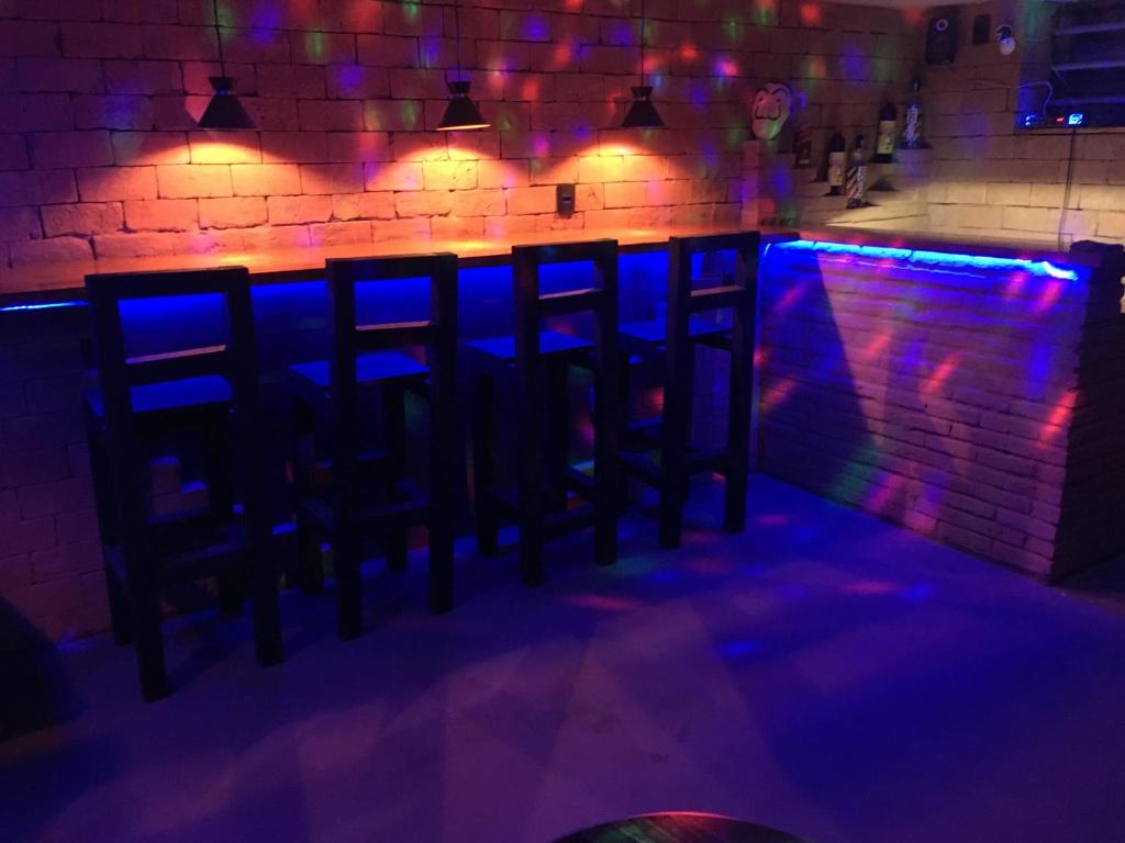 uma fila de cadeiras num bar com luzes azuis em Bella Ciao Hostel no Rio de Janeiro