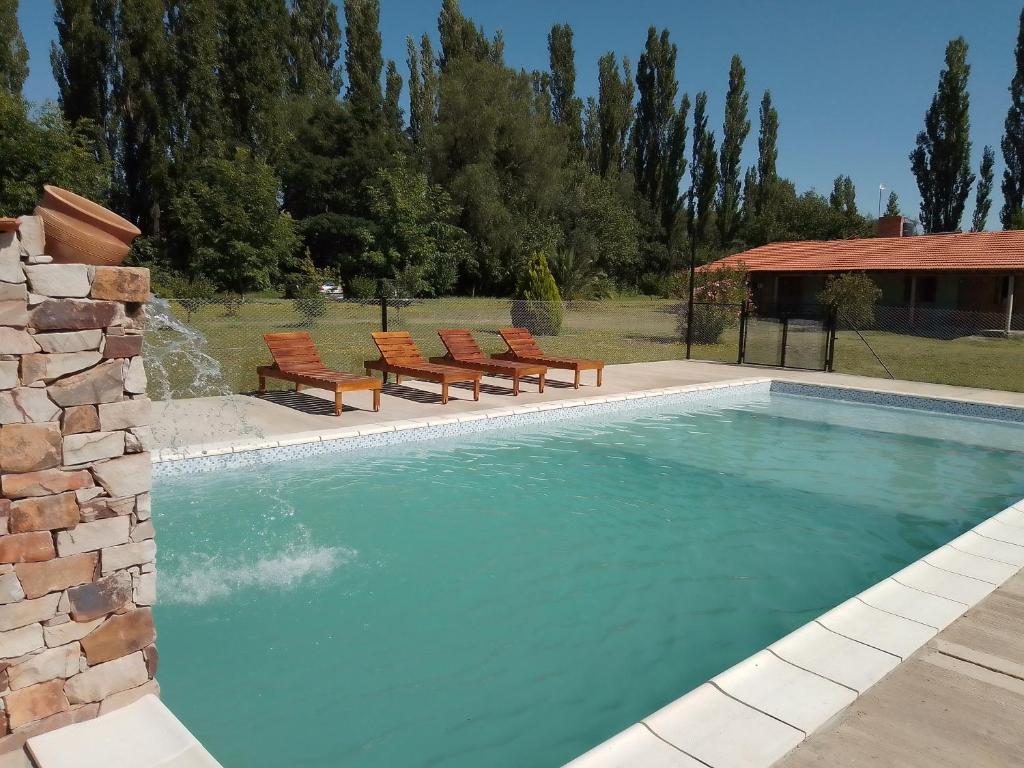 una piscina con 2 sillas y una piscina en cabaña alojamiento Canto de las Aves, en San Rafael