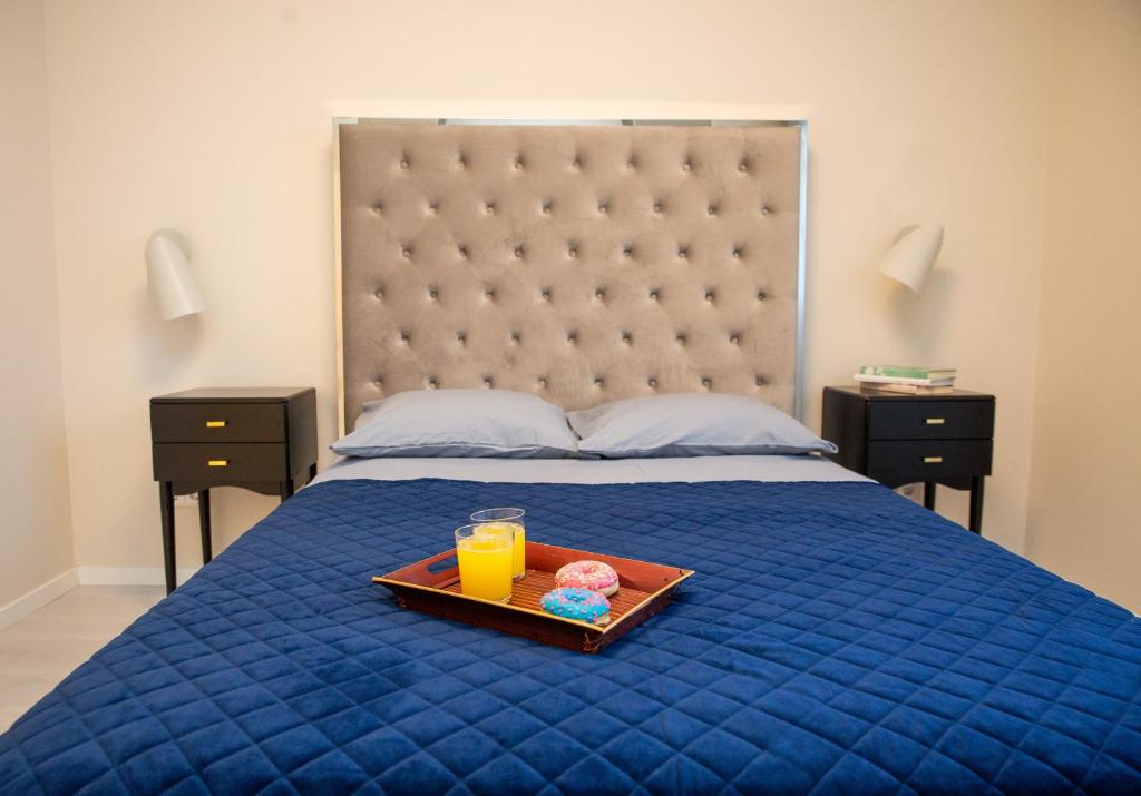 a tray with two donuts and orange juice on a bed at Luxurious Blue&Yellow Apartment in Kaunas Center in Kaunas