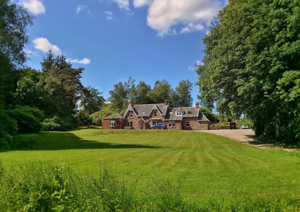 una grande casa su un campo verde con alberi di The West Highland Way Pitches a Glasgow