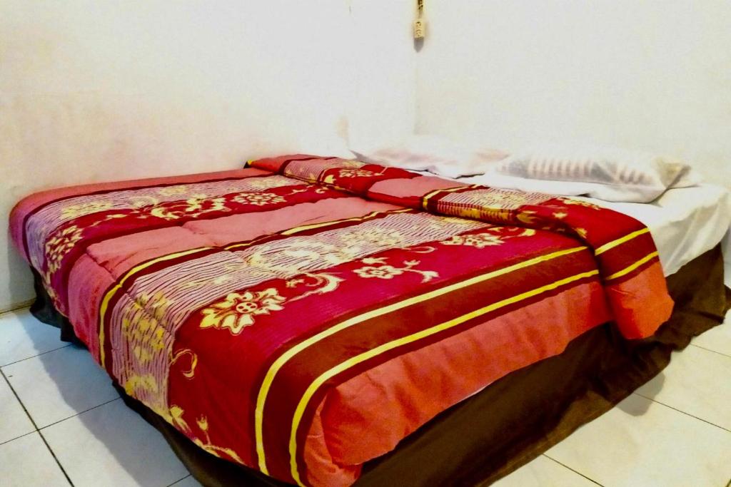 a bed with a red and yellow blanket on it at OYO 90847 Eko Guest House in Makassar