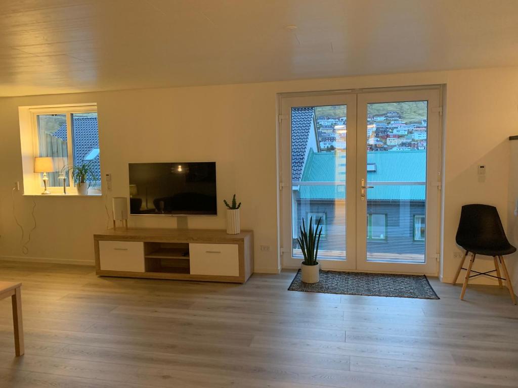een woonkamer met een tv en een groot raam bij Spacious Apartment on N.P.Gøta 8a, Klaksvik in Klaksvík
