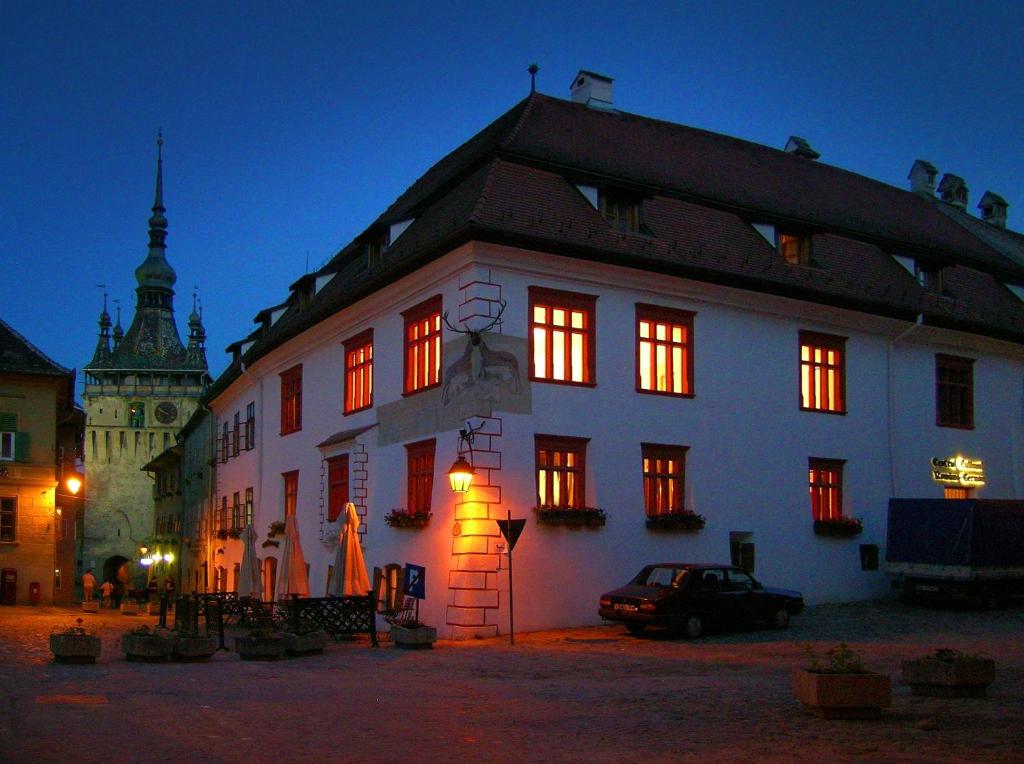 un gran edificio blanco con ventanas iluminadas por la noche en Casa cu Cerb en Sighişoara