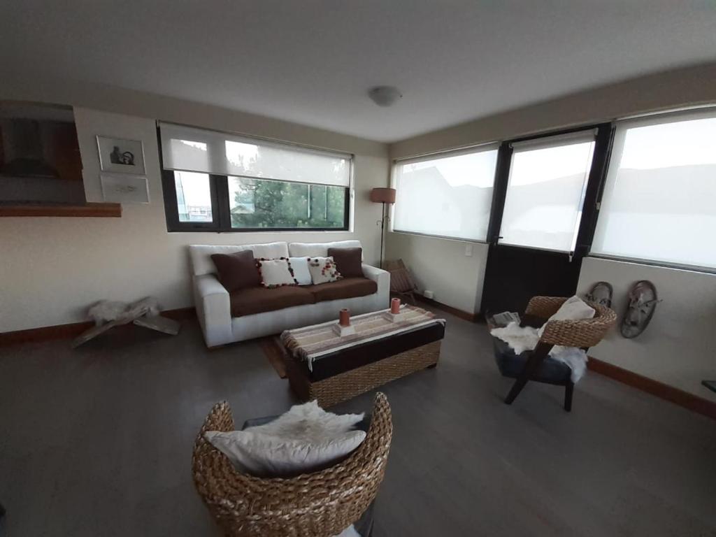 sala de estar con sofá, sillas y ventanas en Cerro Pirámide Alojamiento en Caviahue