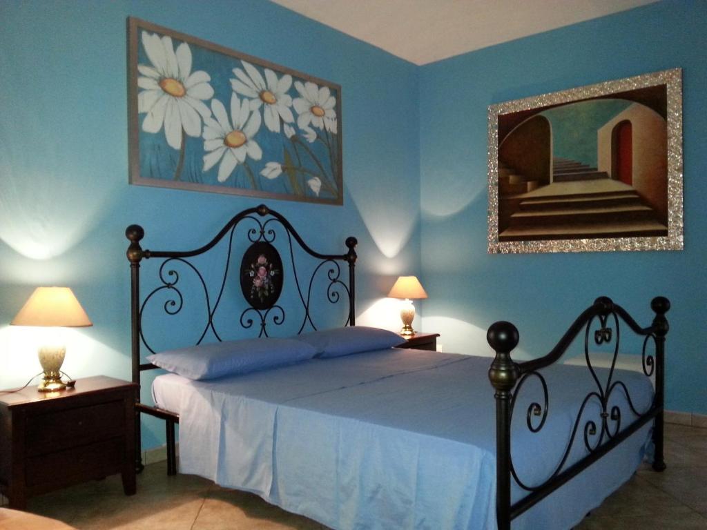 een slaapkamer met een bed met blauwe muren en een spiegel bij B&B Pittoresco in Specchia