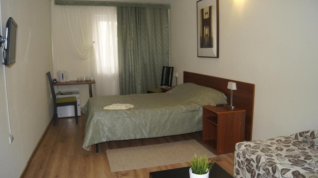 Dormitorio pequeño con cama y mesa en Guest House Comfort, en Ufa
