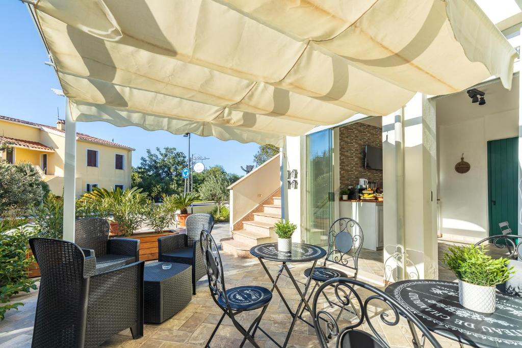 eine Terrasse mit Tischen und Stühlen unter einem großen Sonnenschirm in der Unterkunft Acquazzurra guest house in Tortolì