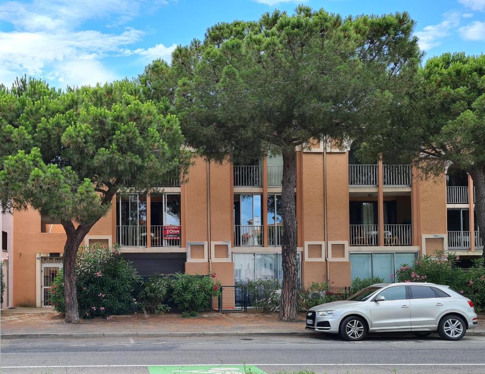 a car parked in front of a building with trees at Superbe T2 climatisé, proche plage avec parking privé in Saint-Cyprien