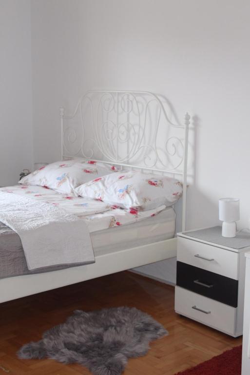 1 dormitorio con cama blanca y mesita de noche en Studio apartman Ivano, en Ðakovo