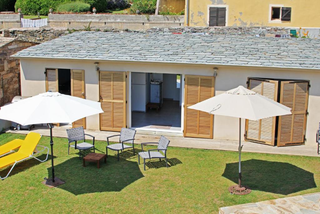 a patio with two white umbrellas and chairs at Maison de 3 chambres a Erbalunga a 10 m de la plage avec vue sur la mer jardin clos et wifi in Erbalunga