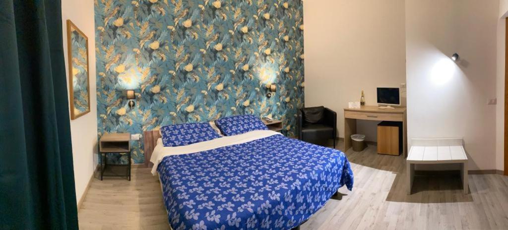 a bedroom with a blue and white bed and a wall at Hotel Ai Tufi in Siena