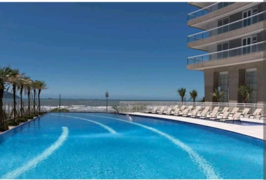 a large swimming pool with chairs and a building at Santos Unlimited 2 Dormitórios, 32o andar com vista Mar! in Santos