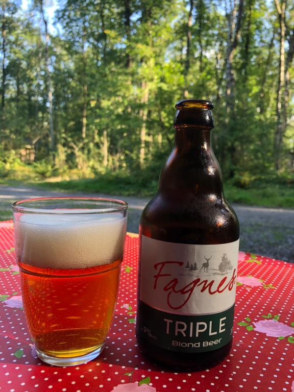 a bottle of beer sitting on a table next to a glass at Forest Lodge in Petit Mesnil