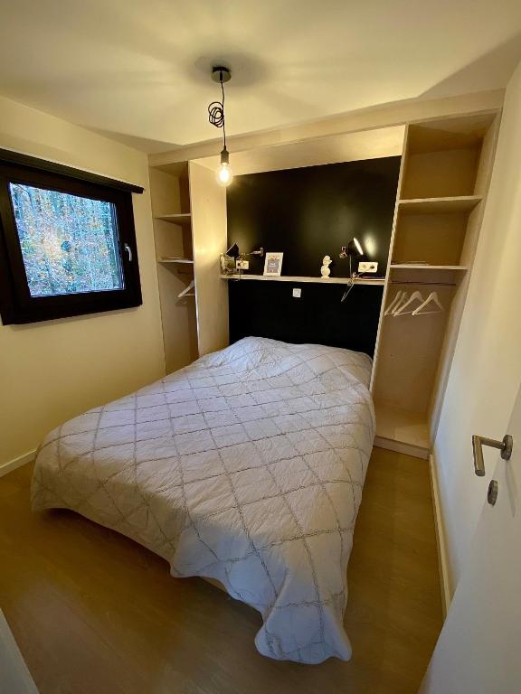 a bedroom with a bed and a window and shelves at Forest Lodge in Petit Mesnil