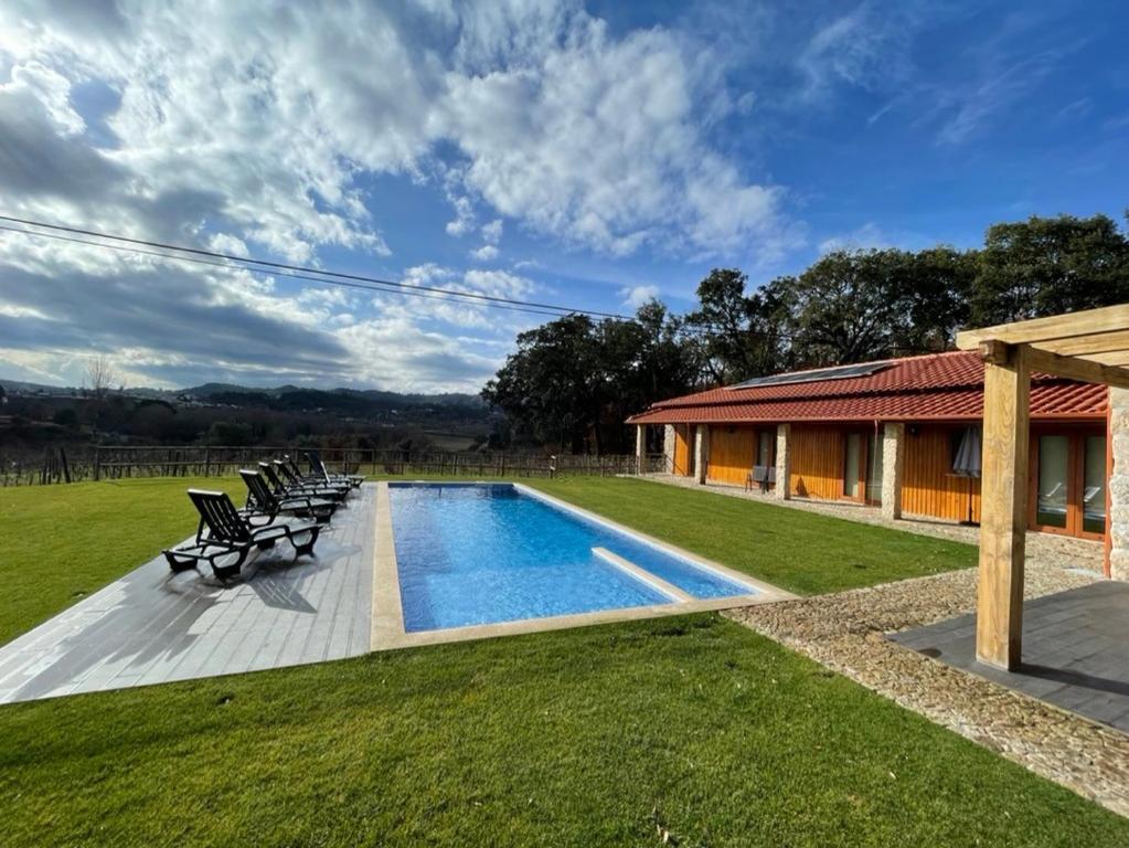 a swimming pool with chairs and a house at Casa de Pelicas - Celorico de Basto in Celorico de Basto