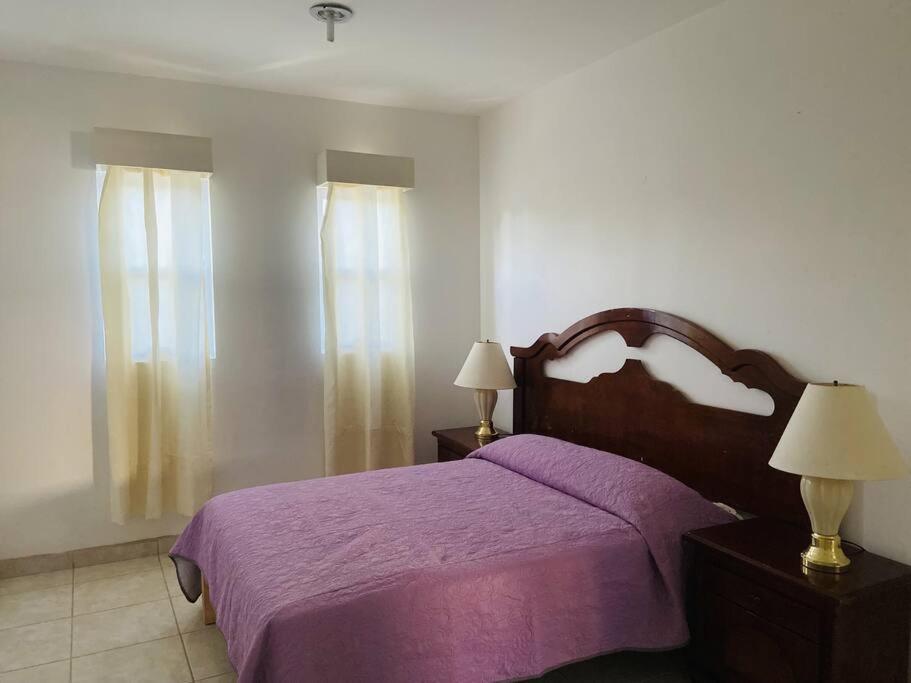 a bedroom with a bed with a purple blanket and two lamps at LOFT en el norte, ideal para estudiantes y familia in Aguascalientes