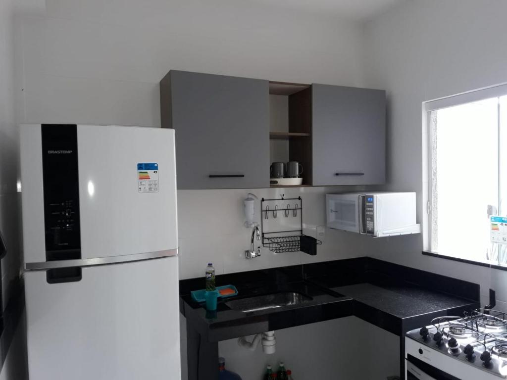 a kitchen with a white refrigerator and a sink at Casa em Costazul - Rio das Ostras in Rio das Ostras