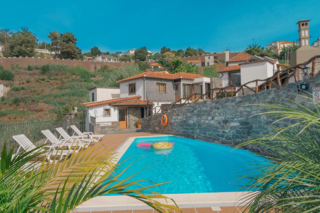 a swimming pool with chairs and a house at Vila Maria Quinta 13 in Calheta